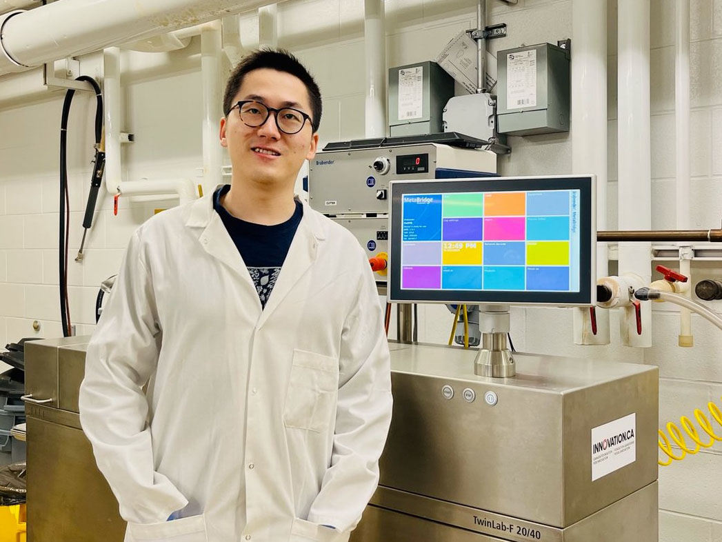 Yikai Ren with the extruder used for producing pet food in the USask Department of Food and Bioproduct Sciences. (Photo: Submitted).