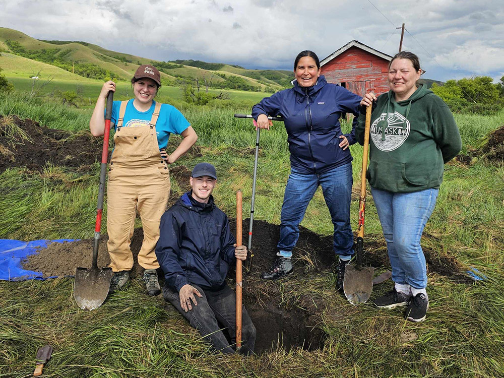 People standing around a dug soil pit