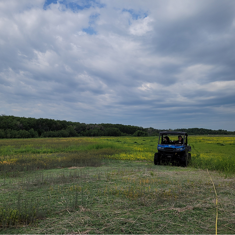 Two people riding in a side by side vehicle to collect soil samples