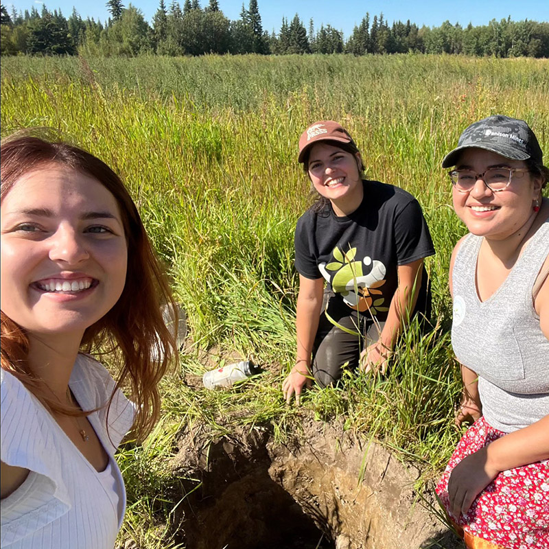 People smiling standing near soil pit