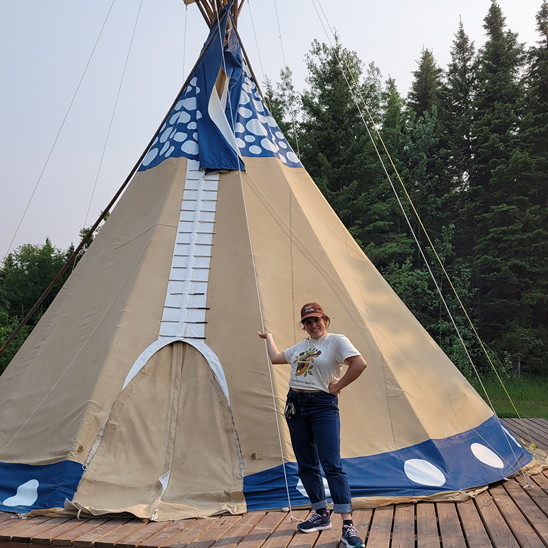 Person standing in front of a tipi - Flying Dust First Nation